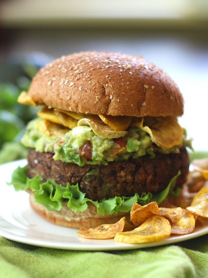 Close Up of a Black Bean Burger Topped with Guacamole and Plantain Chips