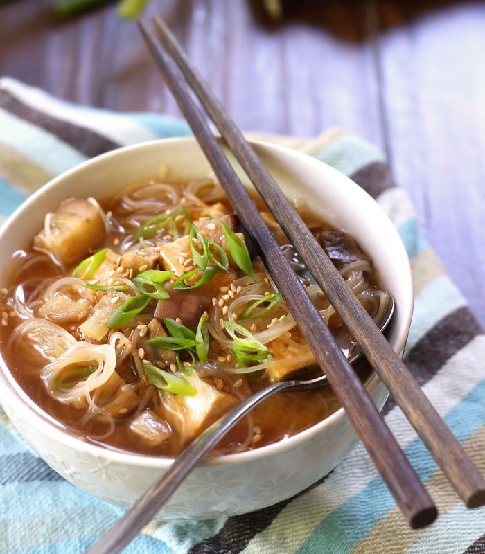 Bowl of Eggplant Noodle Soup on a Striped Napkin with Spoon and Chopsticks
