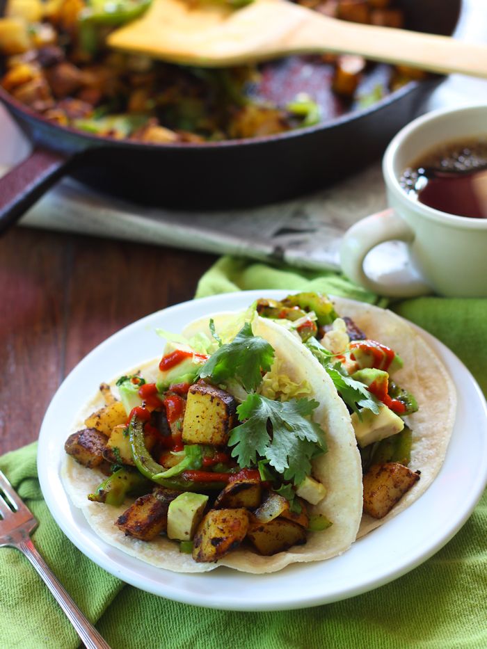 Two Curried Potato Tacos on a Plate with Tea Cup and Skillet in the Background