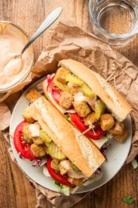Overhead View of Two Halves of a Vegan 'Po Boy Sandwich on a Plate with Remoulade Sauce on the Side
