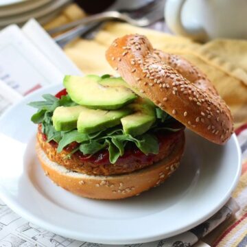 Chickpea burger on a bagel with avocado slices on top.