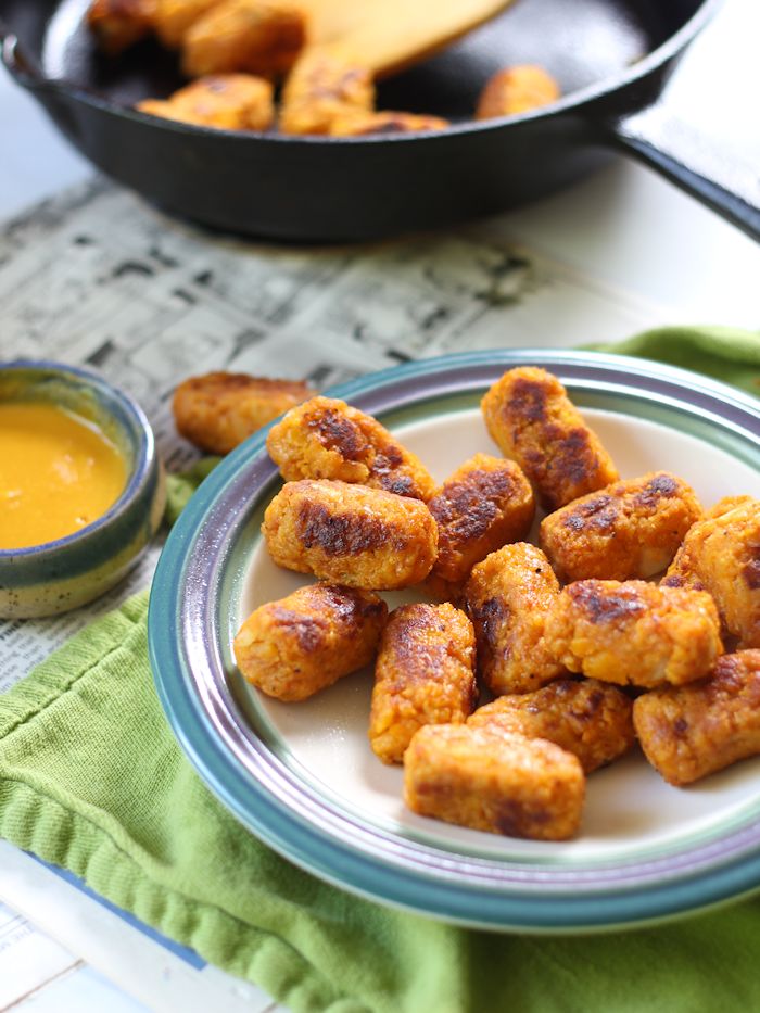 Plate of Butternut Squash Tots with Skillet and Dish of Mustard Sauce in the Background