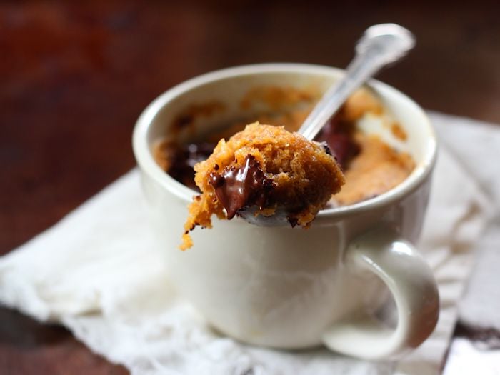 Spoon Sitting on Top of a Chocolate Chip Pumpkin Mug Cake Holing a Scoop of Cake