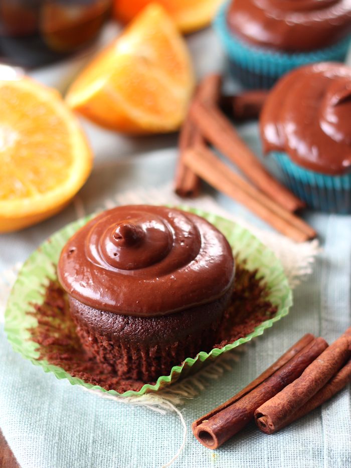 Two Vegan Mulled Wine Chocolate Cupcakes Surrounded by Orange Slices and Cinnamon Sticks