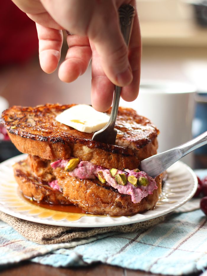 Pair of Hands with Fork and Knife Cutting into a Stack of Stuffed Vegan French Toast