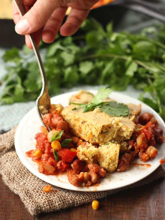 Hand with Fork Digging into a Slice of Vegan Tamale Pie on a Plate