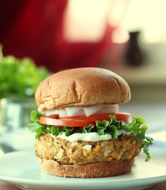 Close Up of a Chipotle Lentil Burger on a Bun with Lettuce, Tomato, and Onion
