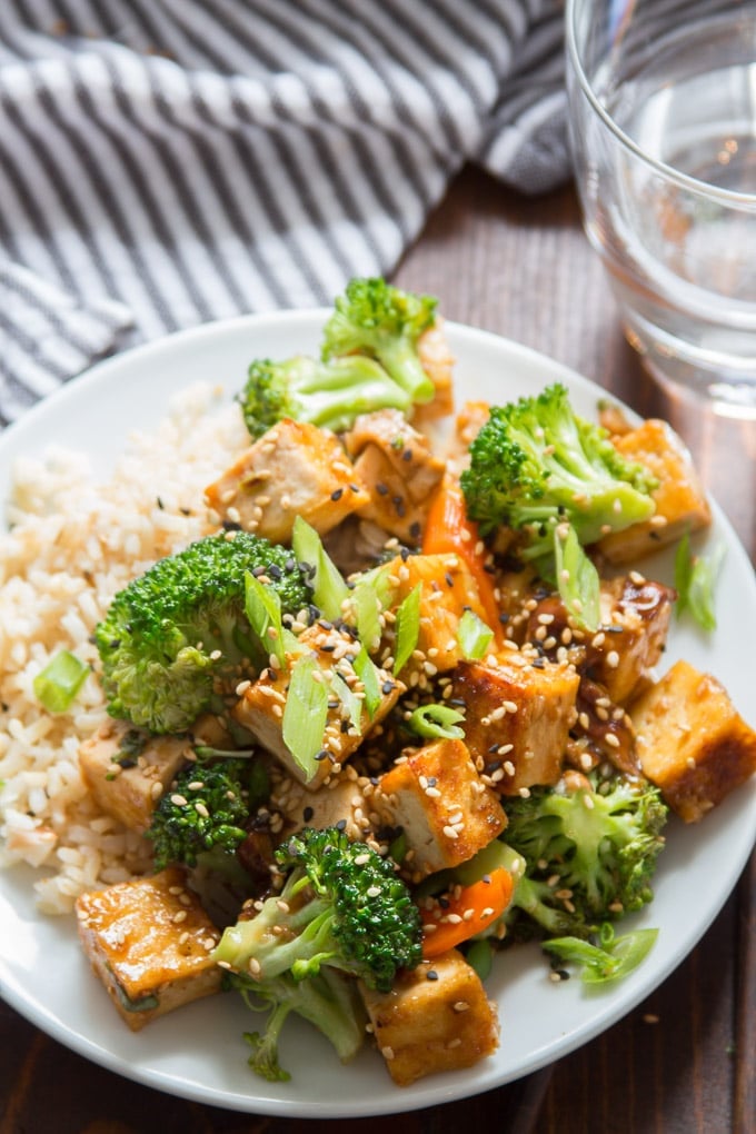 Tofu Stir-Fry on a Plate with Water Glass and Napkin in the Background