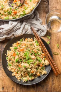 Wooden Table Set with Skillet, Water Glass, and a Plate of Cauliflower Fried Rice