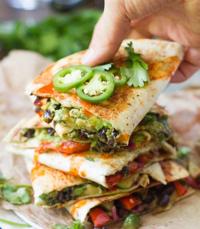 Hand Grabbing The Top Slice from a Stack of Vegan Quesadilla Slices