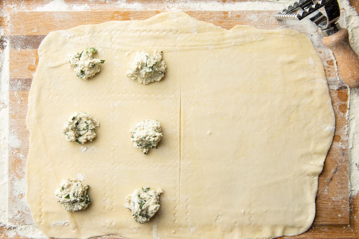 Rolled vegan pasta dough with dollops of vegan ravioli filling arranged on top.