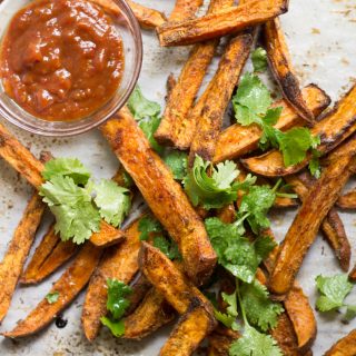 Overhead View of a Scattering of Sweet Potato Jerk Fries with Bowl of Sauce and Fresh Cilantro