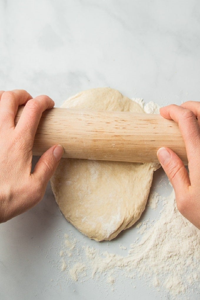 Pair of Hands Rolling Vegan Naan with a Rolling Pin