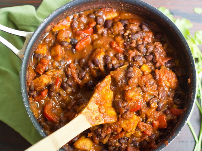 A Pot of Black Bean Plantain Chili with Wooden Serving Spoon