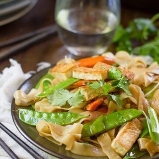 Close Up of Tofu Chow Fun on a Plate with Water Glass in the Background