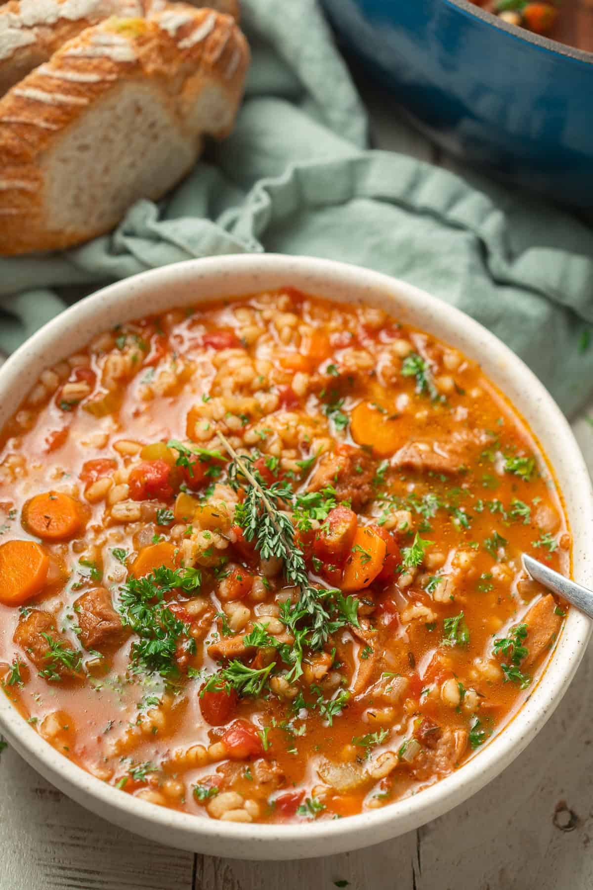 Bowl of Vegan Beef Barley Soup with bread in the background.