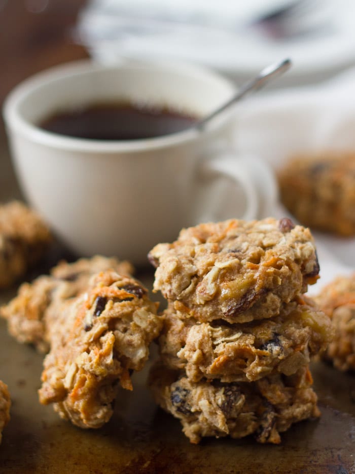 Stack of 3 Morning Glory Breakfast Cookies with a Fourth Cookie Leaning Against the Stack, Coffee Cup in the Background