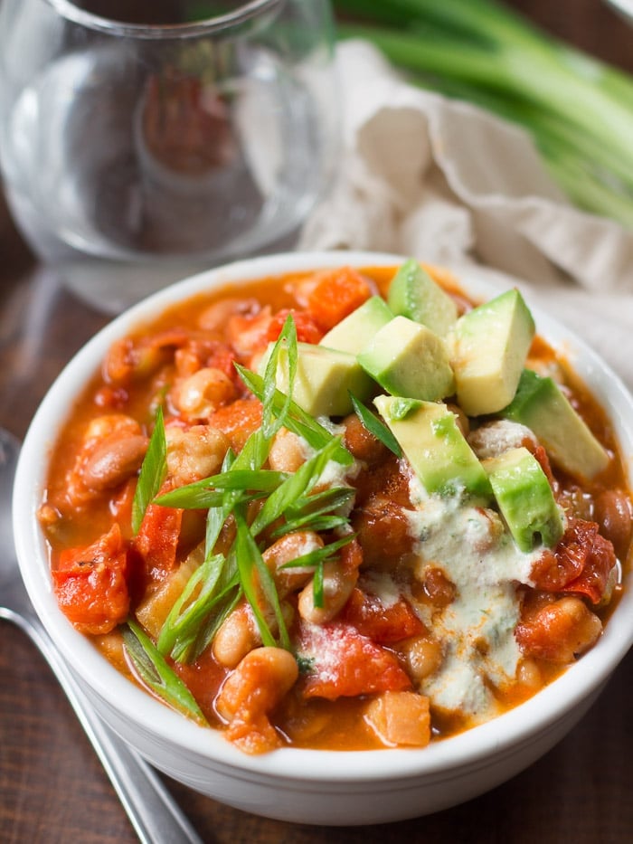 Bowl of Buffalo Chickpea Chili Topped with Cashew Ranch, Avocado Pieces and Scallions
