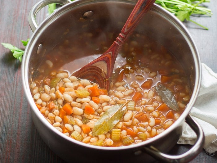 Cooked White Beans and Veggies in a Pot with Wooden Spoon