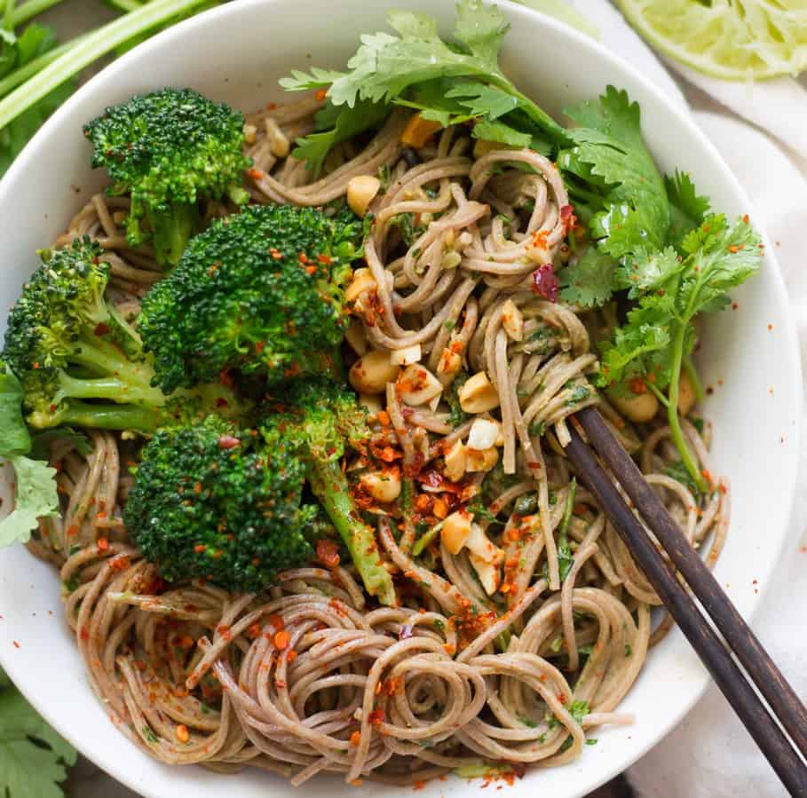 Bowl of soba noodles with peanut sauce and broccoli.