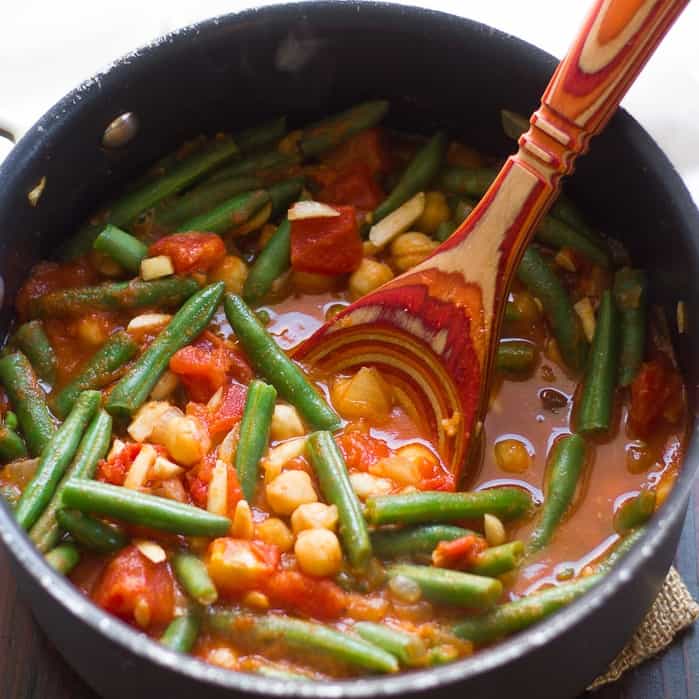 Pot of green bean stew with wooden spoon.