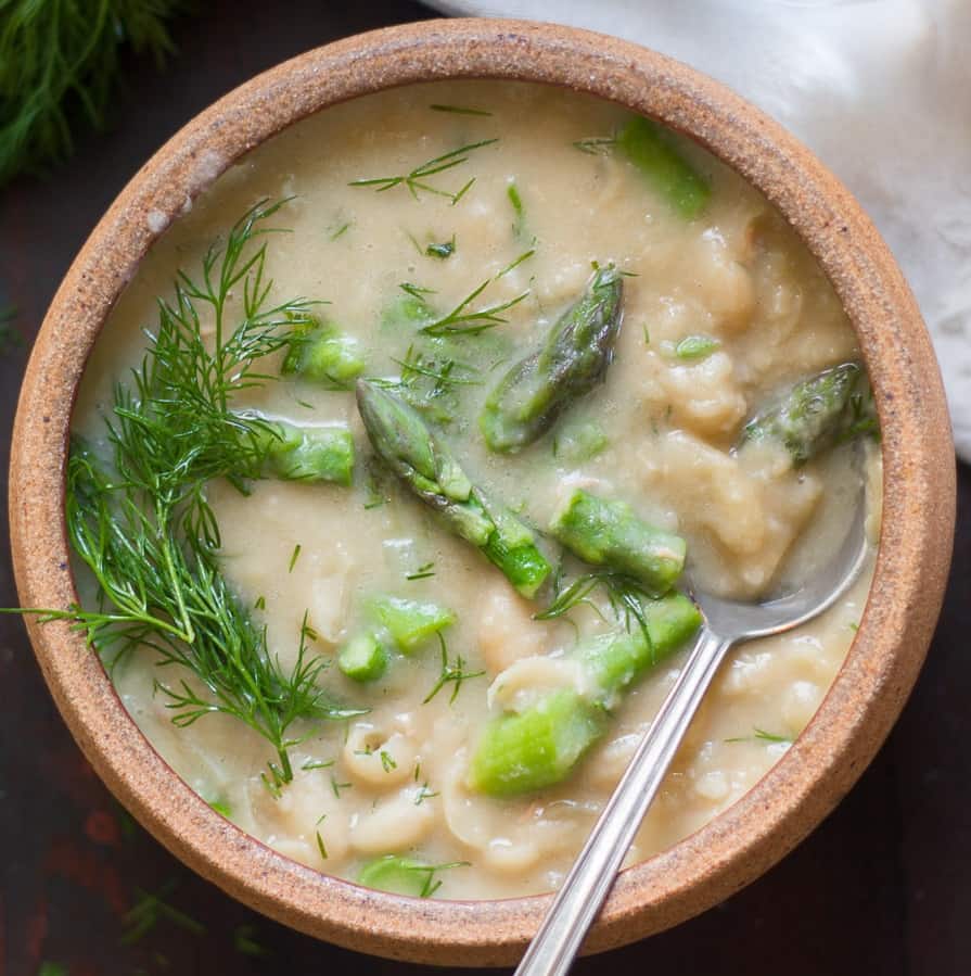 Bowl of white bean asparagus soup with a spoon.