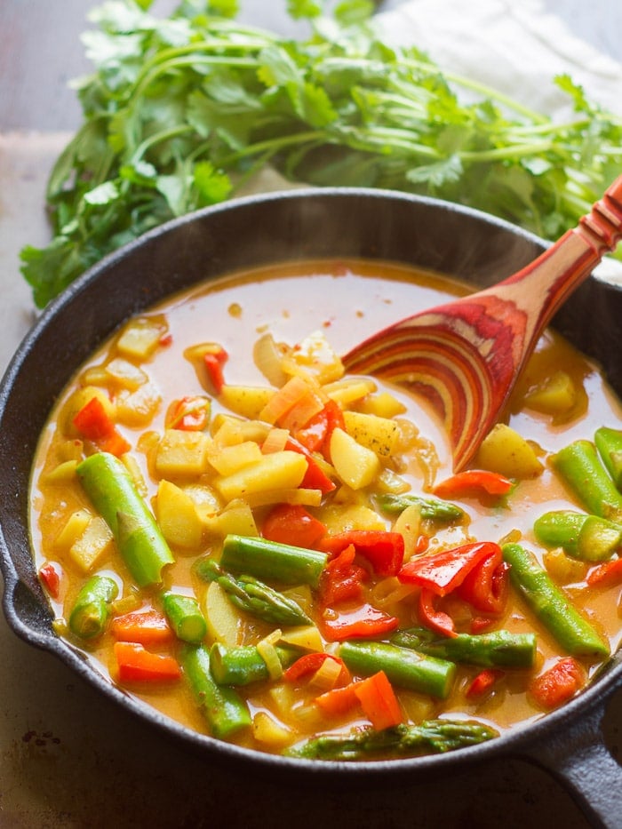 Skillet of Golden Spring Vegetable Thai Curry with Wooden Spoon