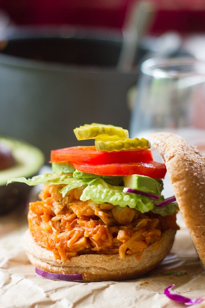 Half of a Sandwich Bun Topped with Maple Buffalo Pulled Jackfruit, Lettuce, Tomato and Pickle Slices