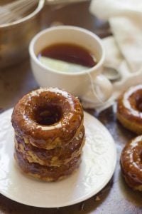 Stack of Three Salted Coconut Caramel Gazed Baked Doughnuts on a Plate with Tea Cup in the Background