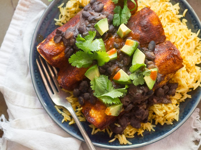 Close Up of Black Bean Smothered Tofu & Plantain Enchiladas Over Rice on a Plate