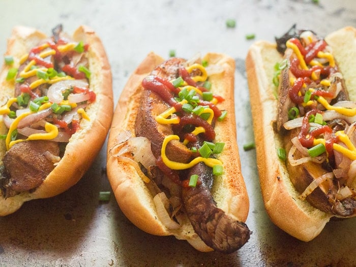 Three Portobello Mushroom Hot Dogs with Mustard, Ketchup, and Chives on Top