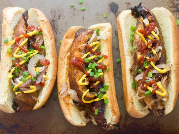 Three Portobello Mushroom Hot Dogs Arranged on a Distressed Baking Sheet