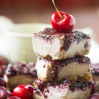 Stack of Three Vegan Cherry Cheesecake Bars with a Fresh Cherry on Top