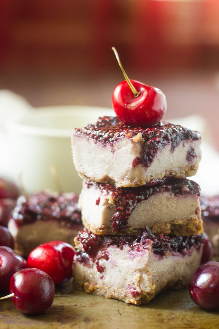 Stack of Three Vegan Cherry Cheesecake Bars with a Fresh Cherry on Top