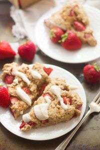 Two Vegan Strawberry Scones on a Plate with Fork and Strawberries in the Background
