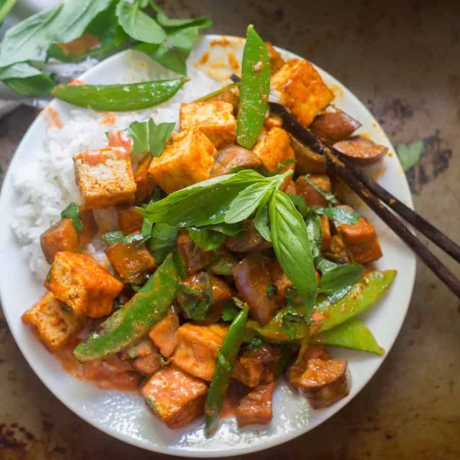 Red curry tofu and eggplant stir-fry on a dish with chopsticks.