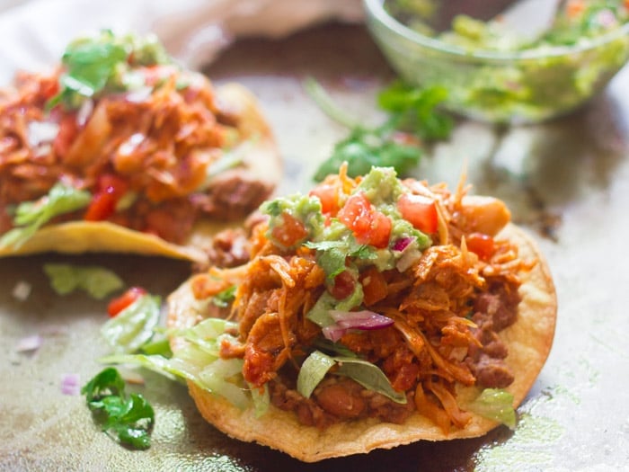 Close Up of a Jackfruit Tinga Tostada with a Second Tostada and Guacamole Bowl in the Background