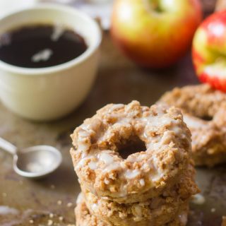 Stack of 3 Vegan Apple Crumble Doughnuts with Coffee Cup, Spoon, and Apples in the Background