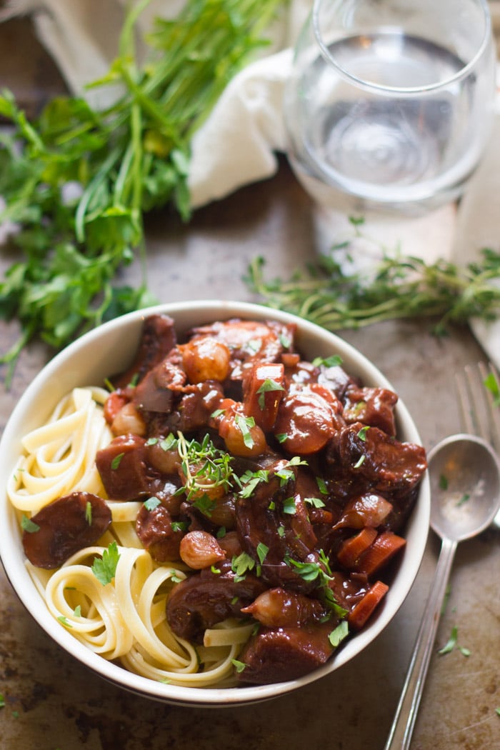 Eggplant Bourguignon in a Bowl with Water Glass and Spoon