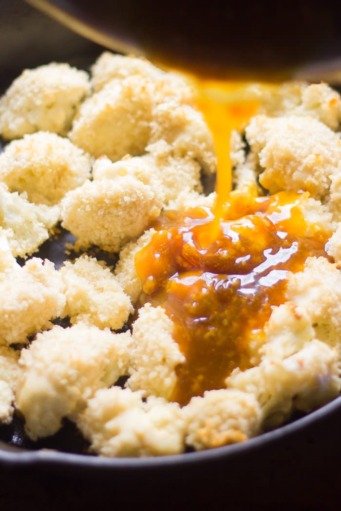 Lemon Sauce Being Poured Over Crispy Cauliflower in a Skillet
