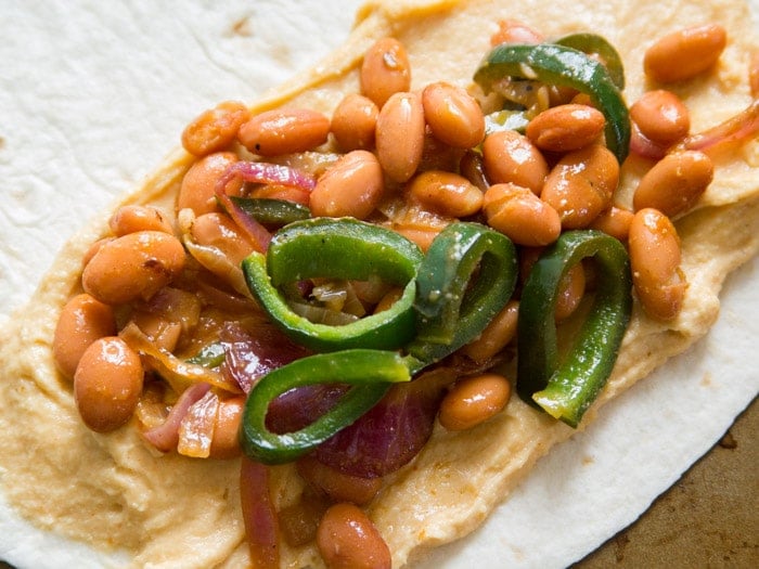 Tortilla Topped with Vegan Cheese, Pinto Beans, Onions and Peppers for Making a Vegan Quesadilla