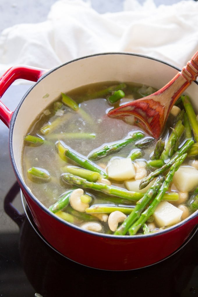 Pot with Potatoes, Asparagus and Cashews Simmering to Make Vegan Cream of Asparagus Soup