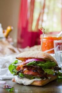 Plant-Based BLT Sandwich with Water Glass and a Jar of Tomato Jam in the Background
