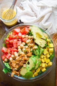 Overhead View of a Vegan Cobb Salad in a Serving Bowl with Napkin, Wooden Spoon and Dressing in a Jar