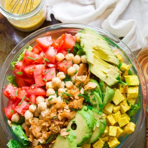 Overhead View of a Vegan Cobb Salad in a Serving Bowl with Napkin, Wooden Spoon and Dressing in a Jar
