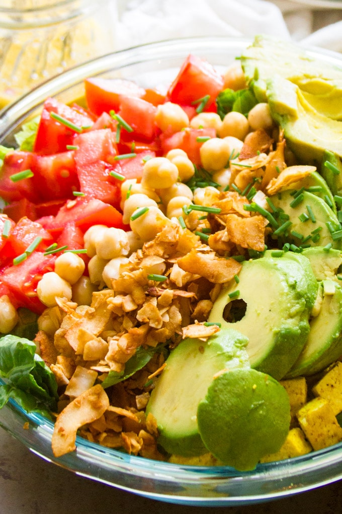 Close Up of a Vegan Cobb Salad Showing Strips of Diced Tomatoes, Chickpeas, Coconut Bacon and Avocado