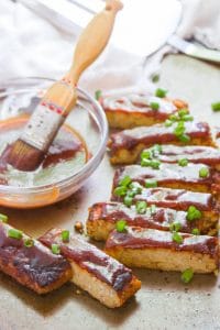 Tempeh Vegan Ribs Arranged Around a Dish of Barbecue Sauce with Basting Brush