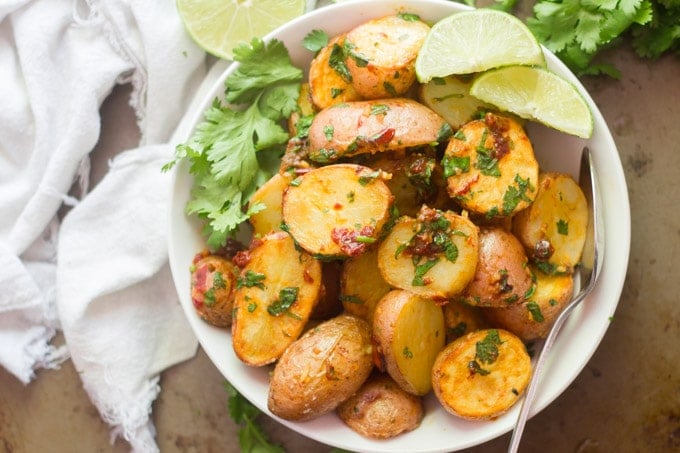 Landscape Overhead View of a Bowl of Chipotle and Lime Roasted Potatoes With Cilantro and Lime Wedges