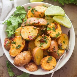 Overhead View of a Bowl of Chipotle and Lime Roasted Potatoes With Cilantro and Lime Wedges