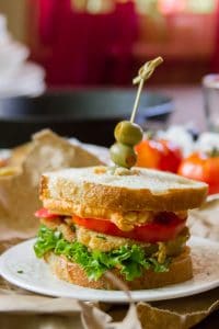 Fried Green Tomato Sandwich on a Plate with Skillet and Tomatoes in the Background